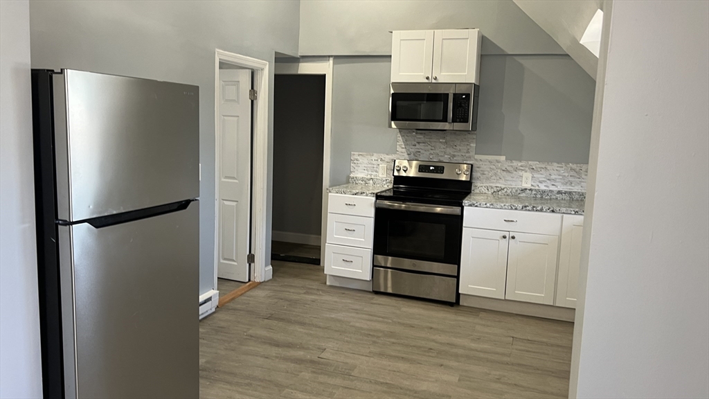 12.5 Benefit Street, Unit 2 Worcester, MA 01610 - Photo 2 of 10 a kitchen with stainless steel appliances a refrigerator stove and microwave