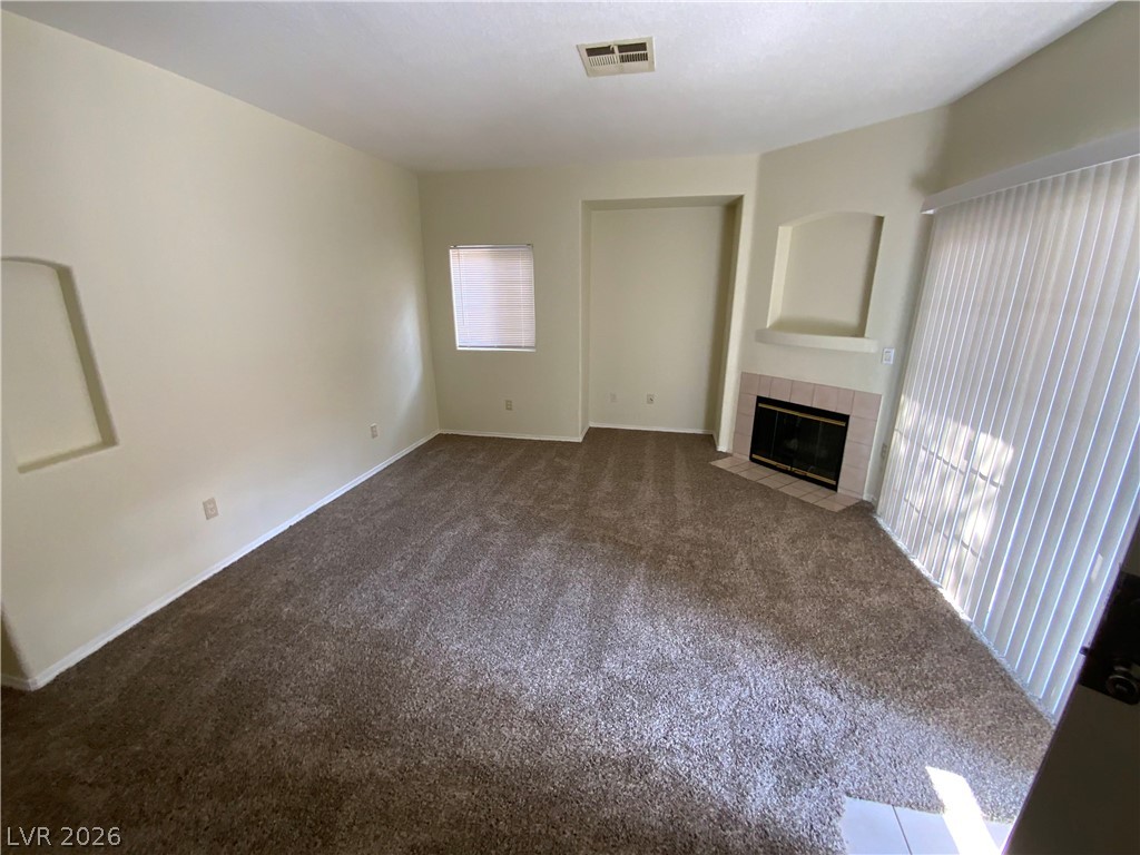4730 East Craig Road, Unit 1091 Las Vegas, NV 89115 - Photo 3 of 14 A cozy living space features soft carpet flooring and a corner fireplace with a mantel.