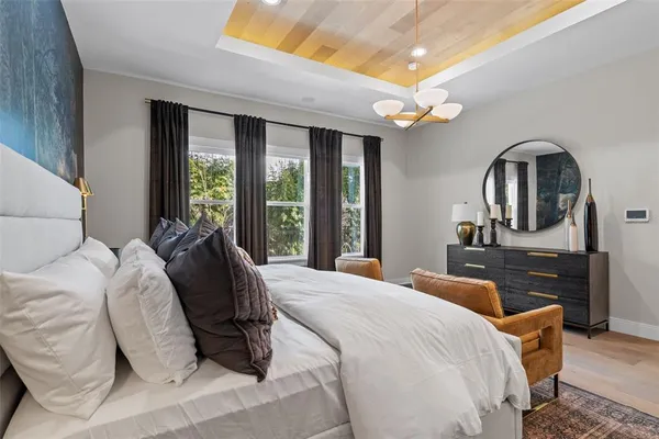 a bedroom with a bed a dresser and large window