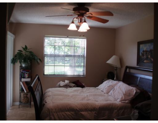 3151 Leewood Terrace, Unit L127 Boca Raton, FL 33431 - Photo 4 of 6 a bedroom with a bed and a chandelier