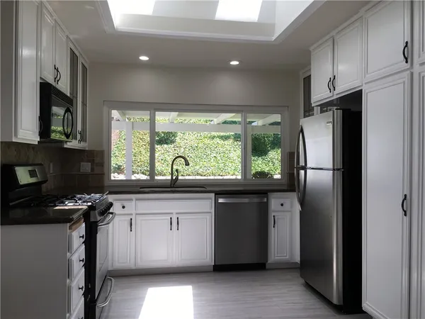 a kitchen with stainless steel appliances granite countertop a refrigerator a sink a stove and a refrigerator