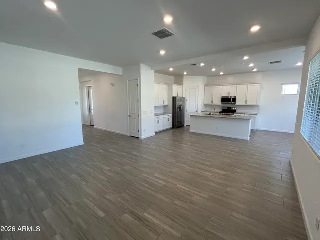 a view of a kitchen with kitchen island a sink wooden floor and a refrigerator