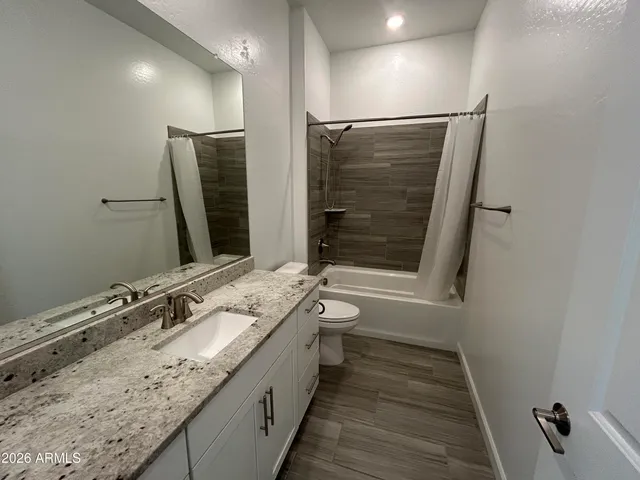 a bathroom with a granite countertop sink a mirror and a shower