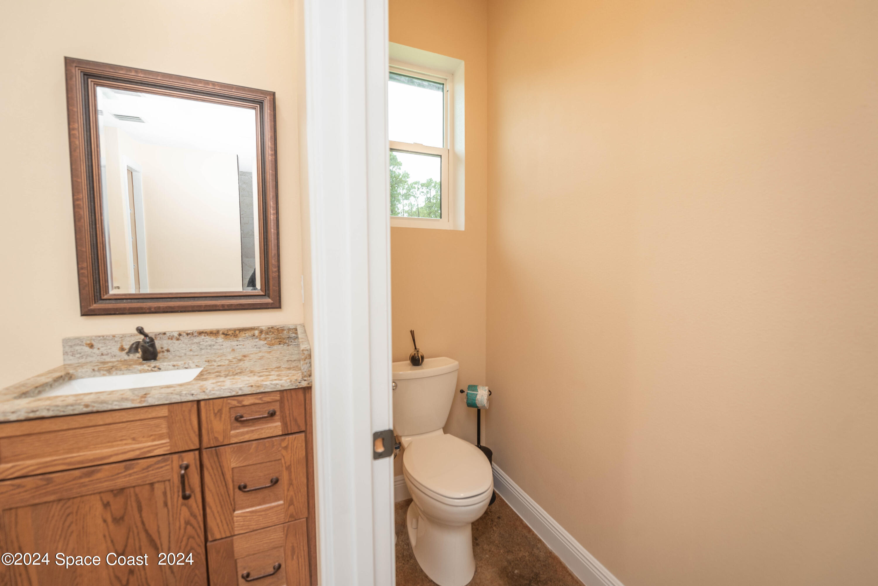 3750 Hield Road Melbourne, FL 32904 - Photo 31 of 63 a bathroom with a granite countertop toilet sink and mirror
