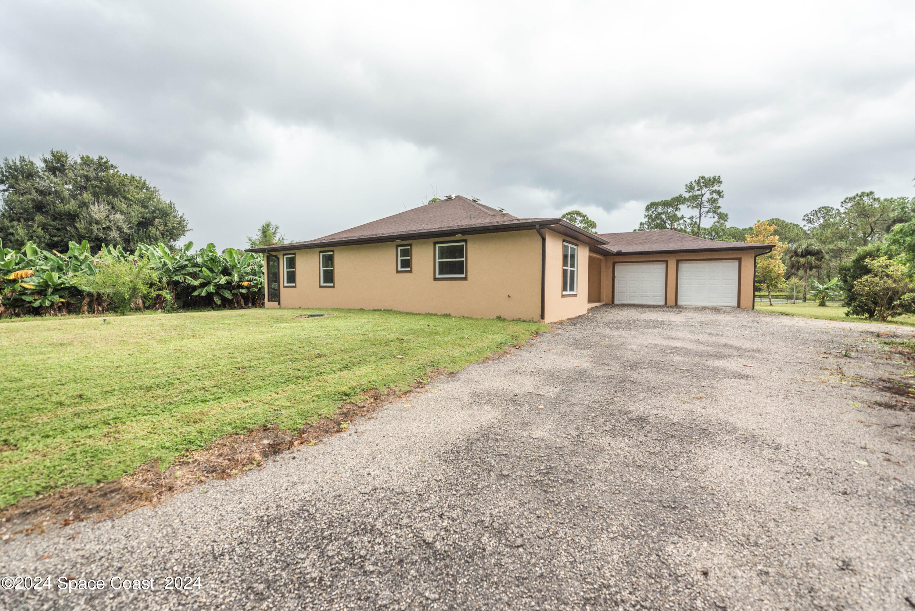 3750 Hield Road Melbourne, FL 32904 - Photo 63 of 63 a white house with a big yard and large trees with wooden fence