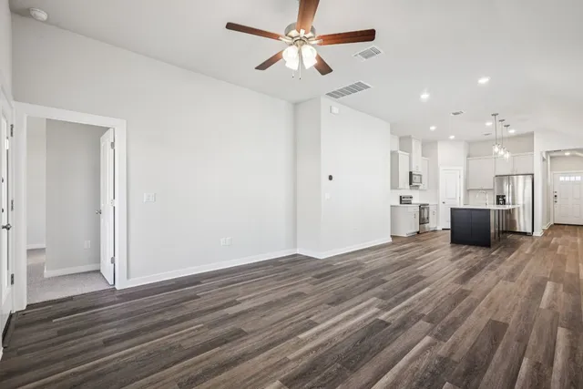 a view of kitchen and empty room with wooden floor