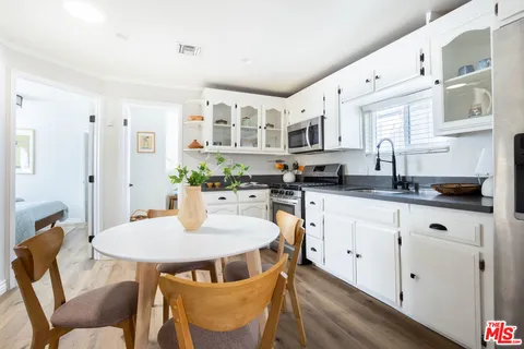 a kitchen with stainless steel appliances granite countertop a table chairs and a refrigerator