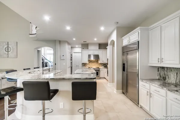 a kitchen with stainless steel appliances kitchen island granite countertop a refrigerator and a stove top oven