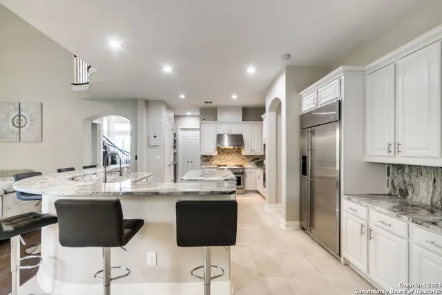 a kitchen with stainless steel appliances kitchen island granite countertop a refrigerator and a stove top oven