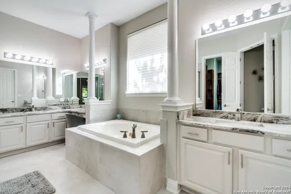 a bathroom with a sink vanity tub and a mirror