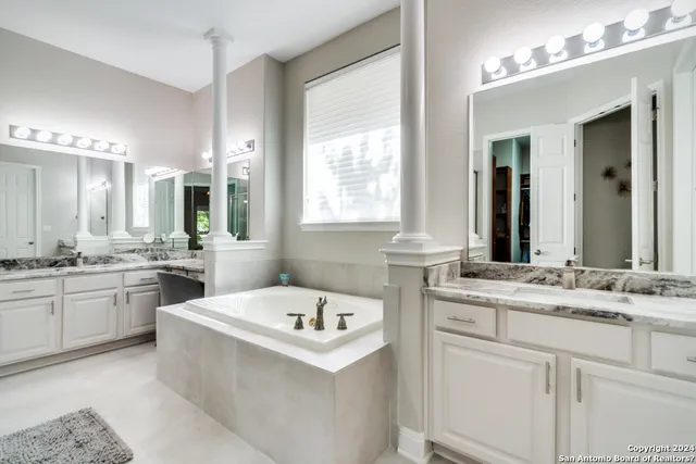 a bathroom with a sink vanity tub and a mirror