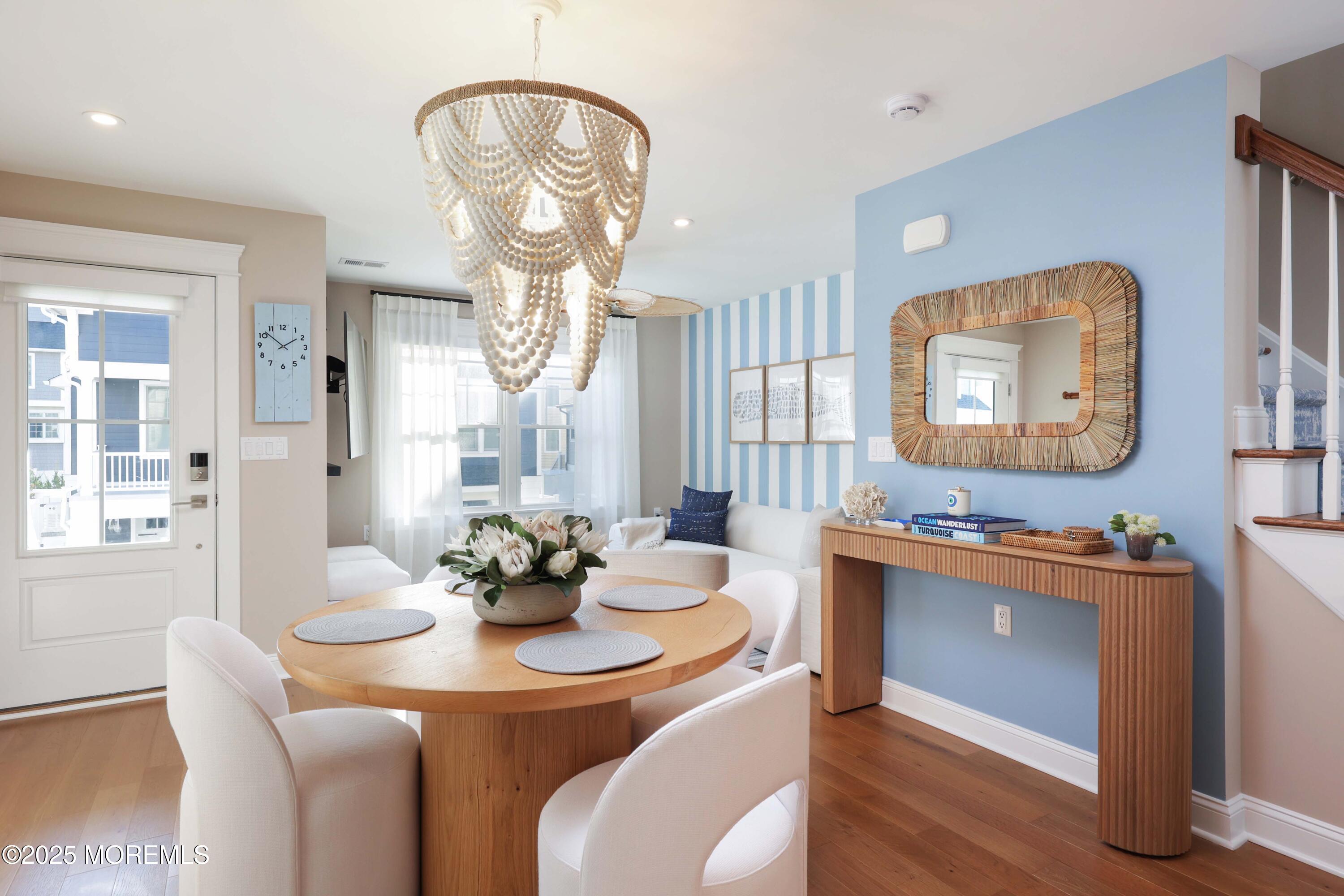 a dining room with wooden floor a chandelier a wooden table and chairs