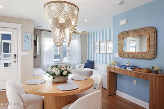 a dining room with wooden floor a chandelier a wooden table and chairs