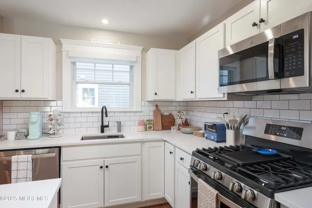 a kitchen with stainless steel appliances a sink a stove a microwave cabinets and a window