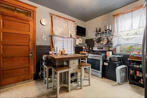 a kitchen with stainless steel appliances kitchen island granite countertop a table chairs and a refrigerator