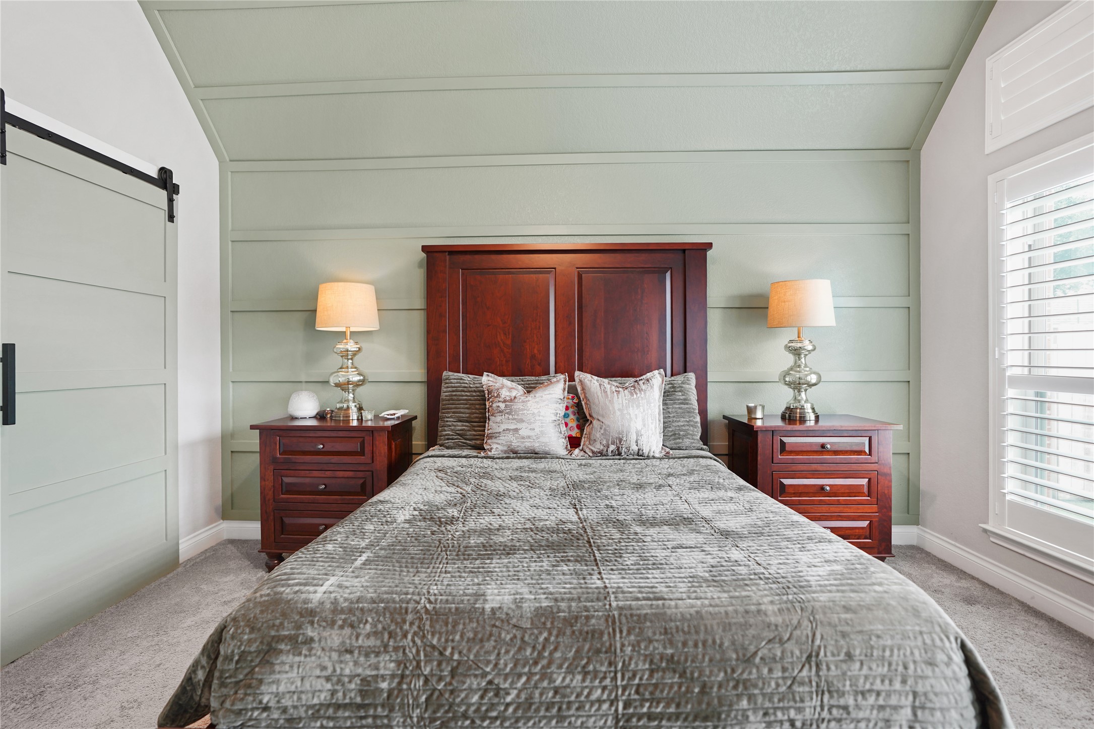 2345 Redwood Ridge Trail Manvel, TX 77578 - Photo 25 of 39 This cozy bedroom features a stylish wooden bed frame, matching nightstands with elegant lamps, a soft carpet, and a light green shiplap accent wall, creating a warm and inviting atmosphere.