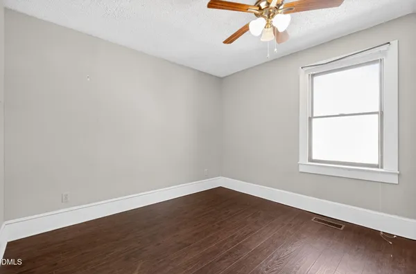 a view of an empty room with window and wooden floor