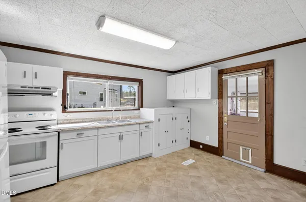 an empty room with wooden floor chandelier fan and windows