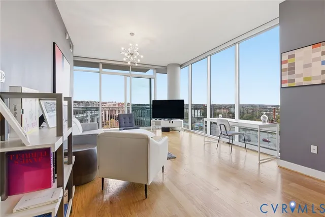 a living room with furniture a flat screen tv and floor to ceiling window