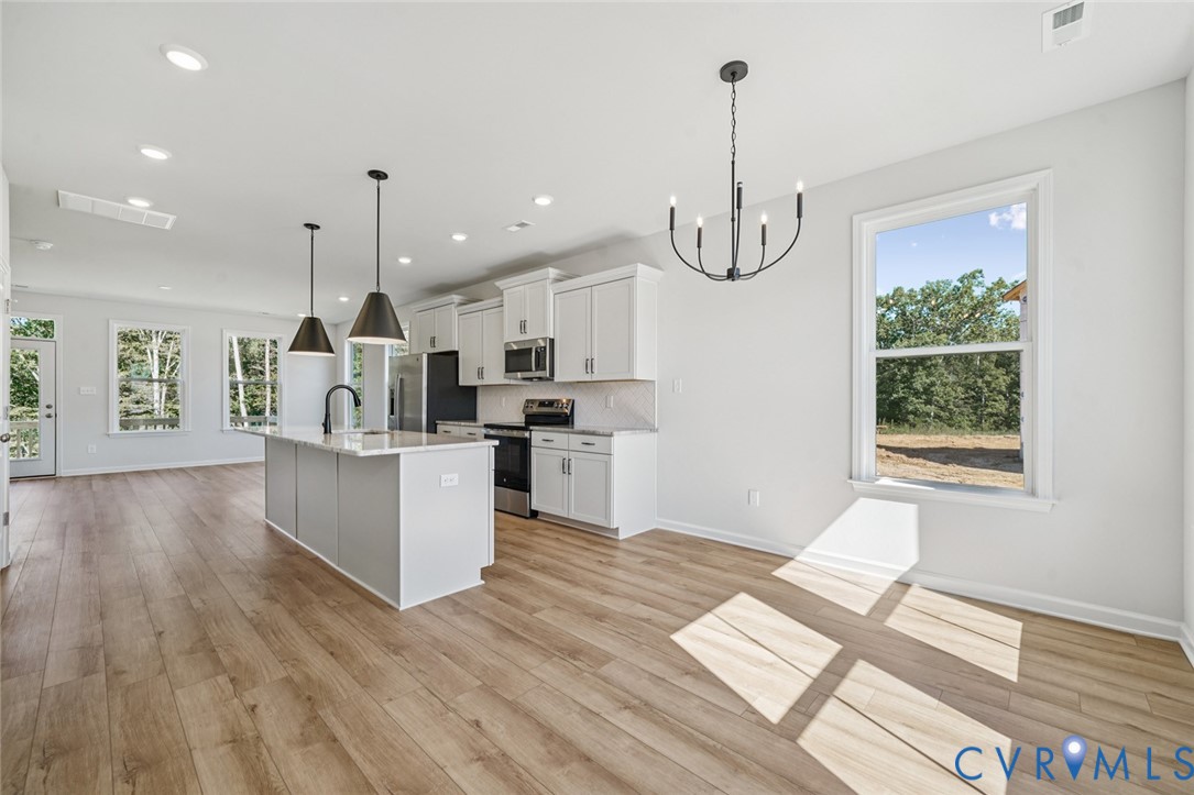 340 Mt Mccauley Way Aylett, VA 23009 - Photo 11 of 48 a kitchen with stainless steel appliances kitchen island wooden floors and white cabinets