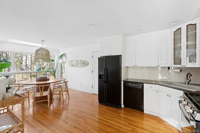 a kitchen with stainless steel appliances granite countertop a dining table chairs refrigerator and sink