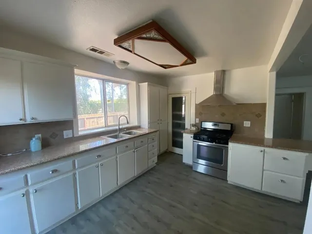 a large kitchen with stainless steel appliances kitchen island granite countertop a sink and cabinets