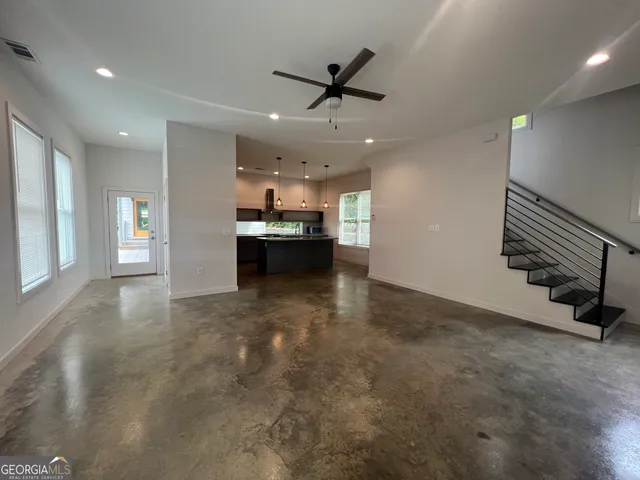 a view of a livingroom with a ceiling fan and kitchen space