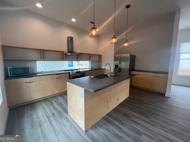 a large kitchen with stainless steel appliances granite countertop a sink and a wooden floors