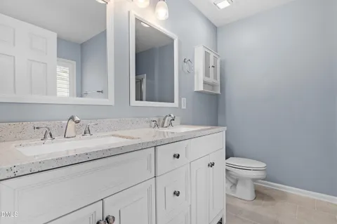 a bathroom with a granite countertop sink a toilet and a mirror