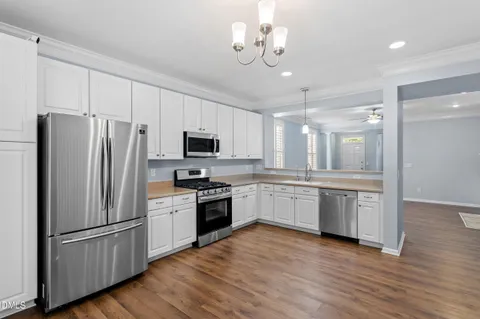 a kitchen with granite countertop stainless steel appliances a refrigerator a sink cabinets and wooden floor