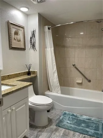 a bathroom with a granite countertop bathtub shower sink and toilet