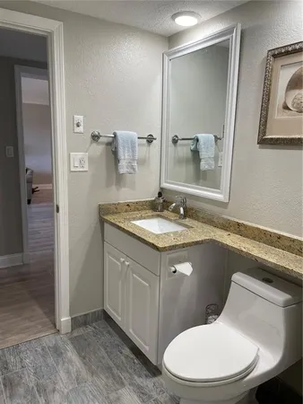 a bathroom with a granite countertop toilet sink and mirror
