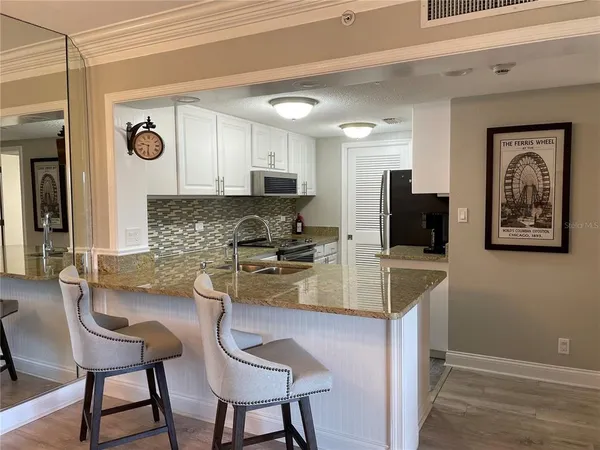 a kitchen with stainless steel appliances granite countertop a stove a sink a microwave a refrigerator and cabinets