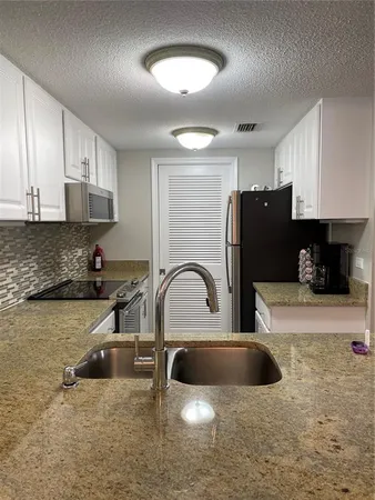 a kitchen with stainless steel appliances granite countertop a sink a stove and a refrigerator