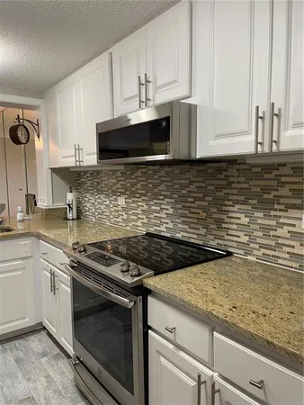 a kitchen with granite countertop a stove sink and cabinets