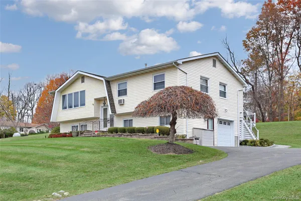 a view of a white house next to a yard with big trees