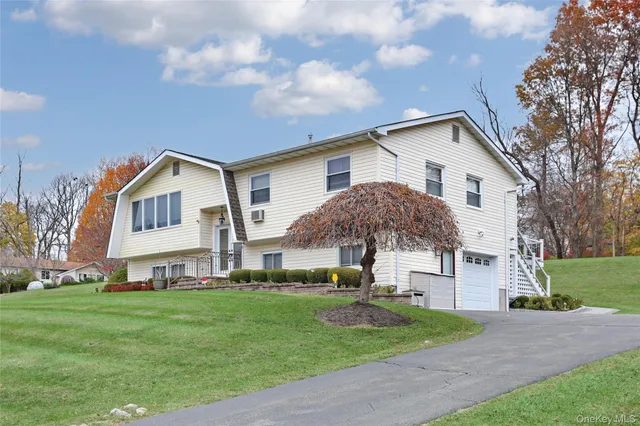 a view of a white house next to a yard with big trees
