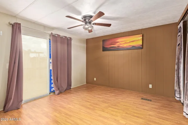 a view of empty room with wooden floor and fan