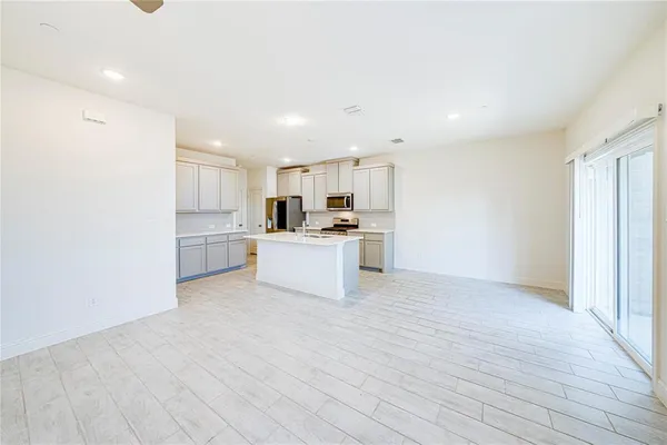 a kitchen with stainless steel appliances kitchen island granite countertop a stove a sink a refrigerator with white cabinets and wooden floor