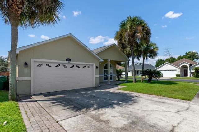 a view of a house with a yard and palm trees