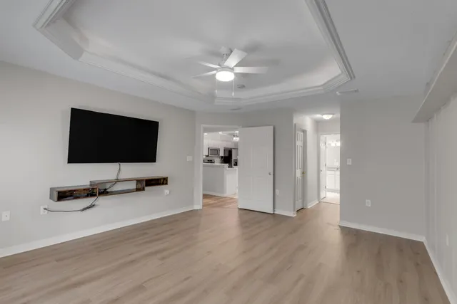 a view of a livingroom with a flat screen tv wooden floor and a ceiling fan