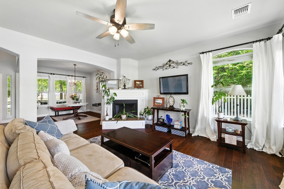 316 Caraway Kyle, TX 78640 - Photo 12 of 39 Living area featuring arched walkways, a ceiling fan, hardwood flooring, and a fireplace with raised hearth
