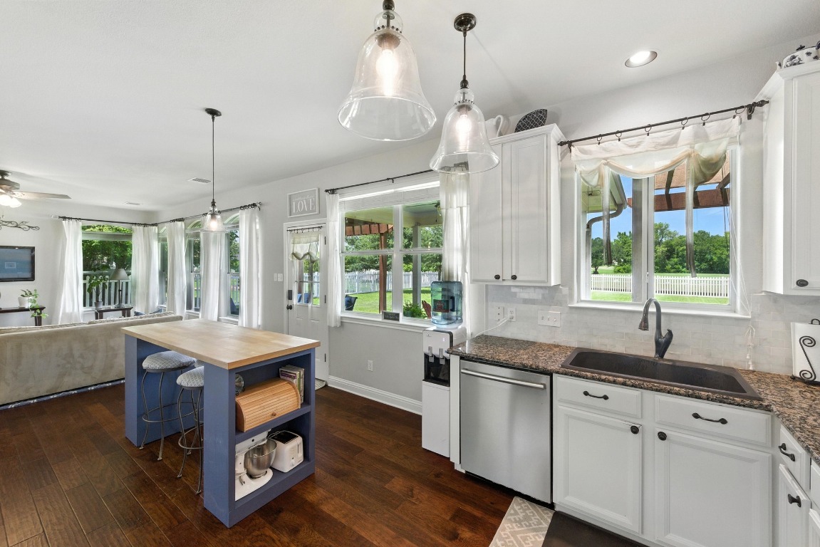 316 Caraway Kyle, TX 78640 - Photo 39 of 39 Kitchen with stainless steel dishwasher, wood flooring, white cabinetry, open floor plan, and dark granite counters