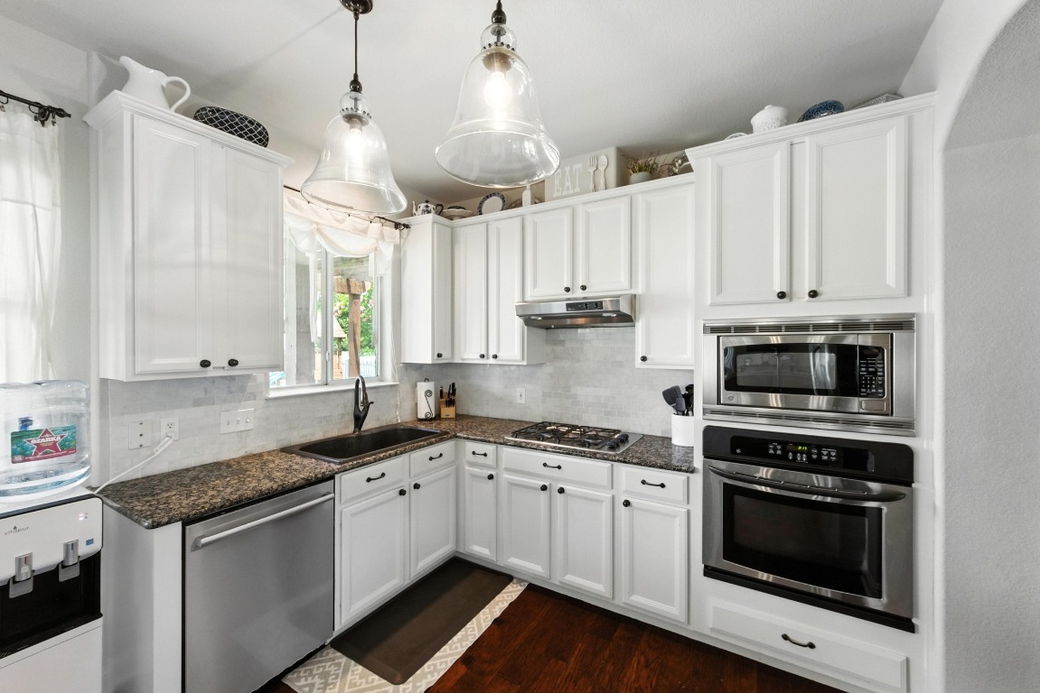 316 Caraway Kyle, TX 78640 - Photo 17 of 39 Kitchen featuring appliances with stainless steel finishes, white cabinetry, dark wood floors, and decorative backsplash