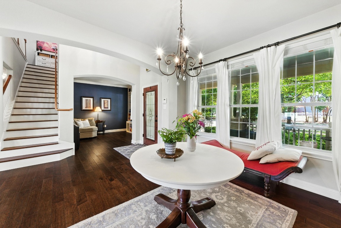 316 Caraway Kyle, TX 78640 - Photo 38 of 39 Dining area with arched walkways, beautiful wood flooring, stairs, and a chandelier