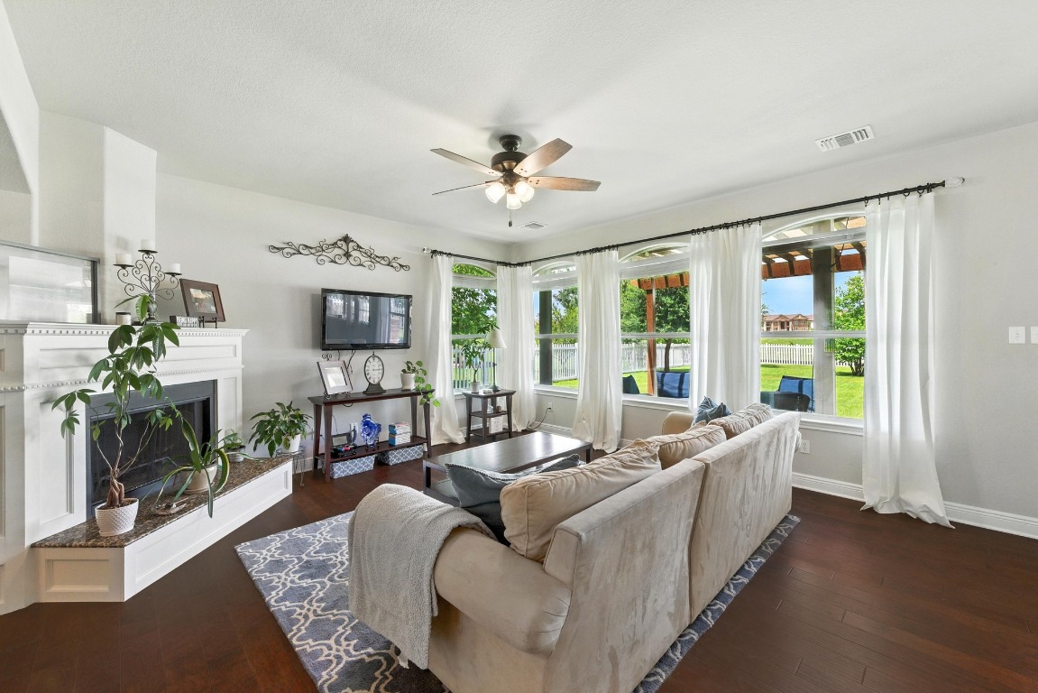 316 Caraway Kyle, TX 78640 - Photo 10 of 39 Living area featuring a ceiling fan, beautiful wood floors, and a fireplace with raised hearth