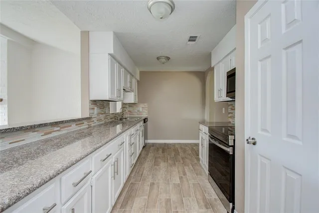 a kitchen with granite countertop a sink and a stove top oven