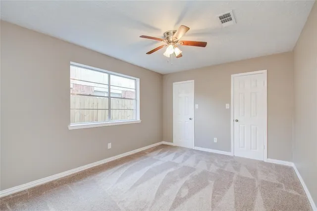 a view of an empty room with chandelier fan and a window