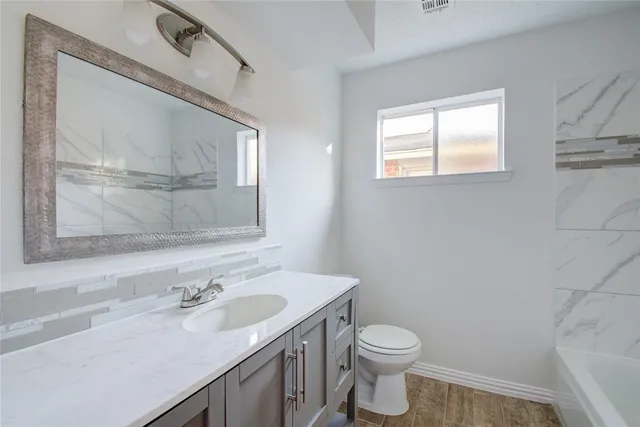 a bathroom with a granite countertop sink toilet and mirror