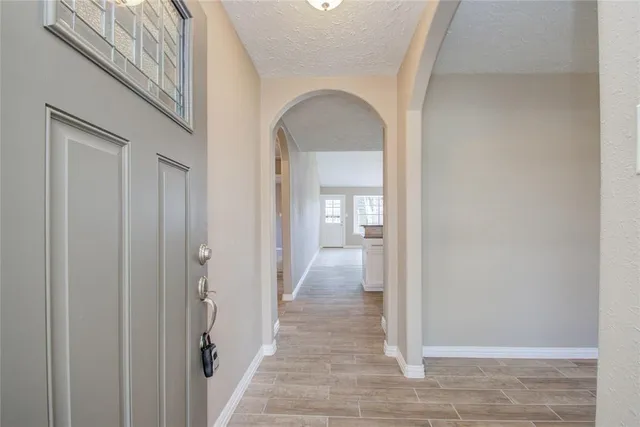 a view of a hallway with wooden floor and a bathroom